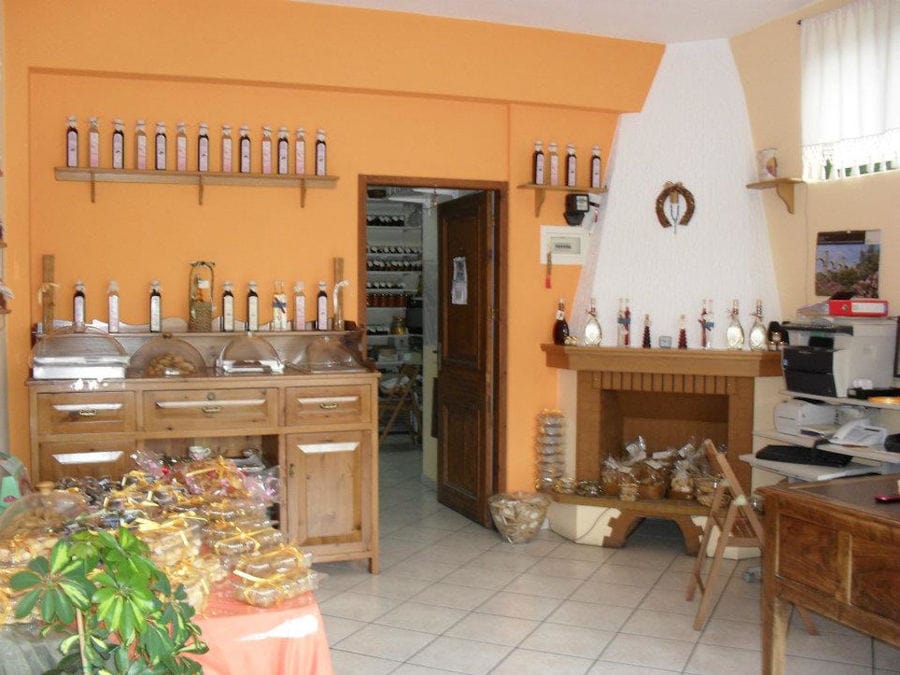 'Agrotouristic Women's Cooperative of Mesotopos Lesvos' store inside with fireplace and bottles on shelves on the wall