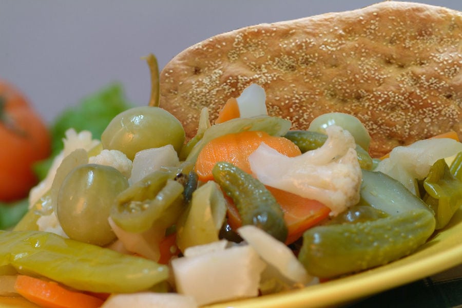 plate with various pickles from 'Pitenis' like peppers and cauliflowers and carrots and a 'lagana' bread in the background