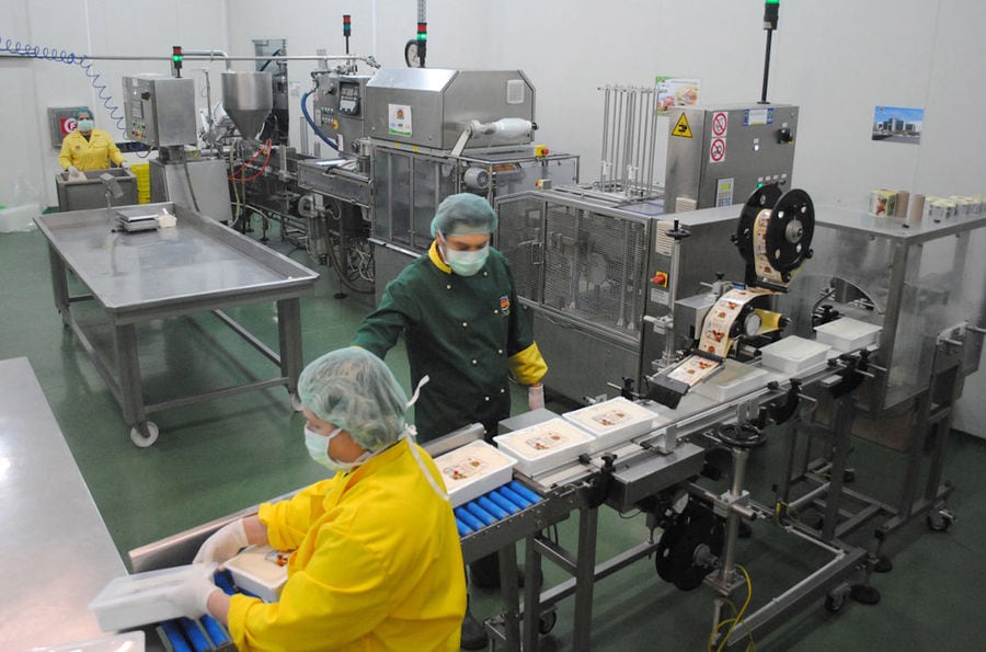 two men using labeling machine and packaging boxes of 'Pitenis' products