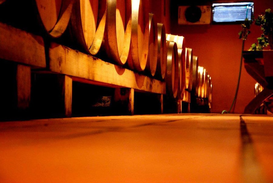 view of the base of lying wooden barrels at 'Aidarini Winery' cellar