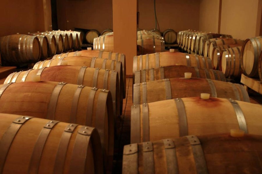 lying wooden barrels in a row at 'Aidarini Winery' cellar