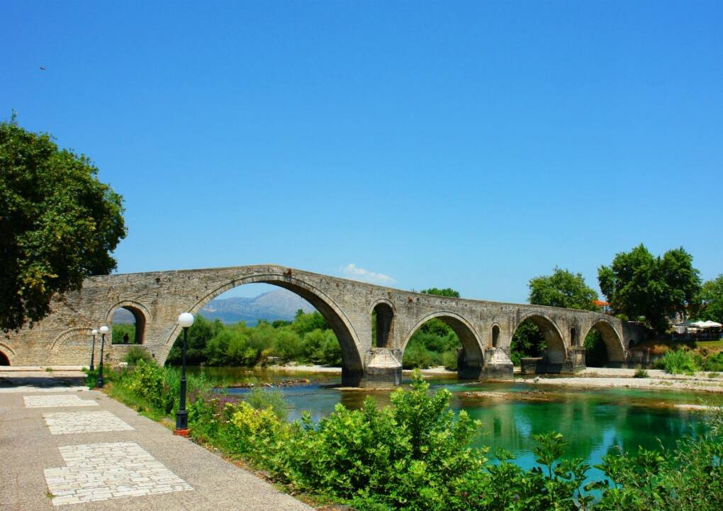 a bridge over water with trees and a path