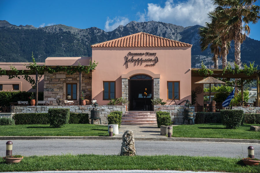 front view of the building that says on upper part Hatziemmanouil Winery with green lawn on both sides