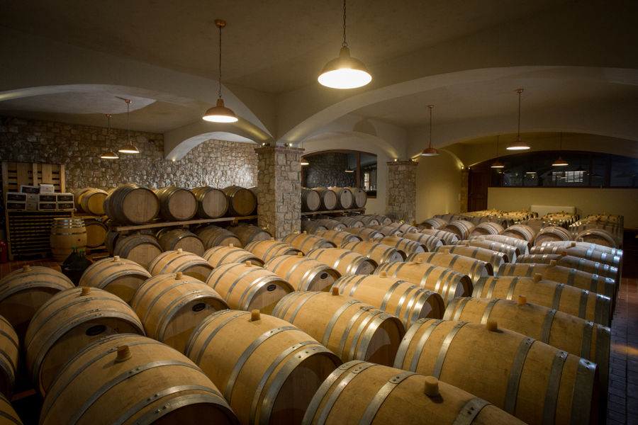 lying wine wooden barrels in a row at illuminated 'Kechris Winery' cellar