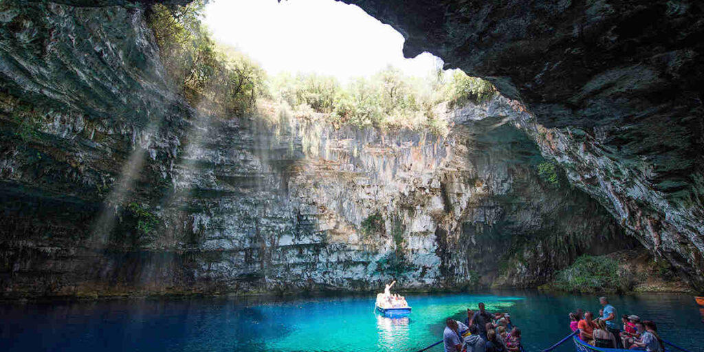 A small boat navigates the vibrant blue waters within a cave, highlighting the natural beauty of the surrounding rock walls.