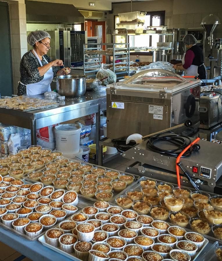 lu1k7xMT_DxDTH0kV_Woman prepare small puddings in plastic bowls with cinnamon on top at Yia yia workshop.jpg