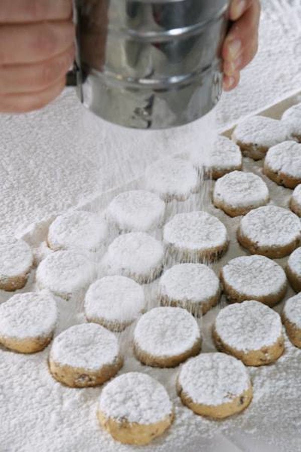 man holding aluminum cylinder and put powdered sugar on the sweets from 'Bekas Family Farm'