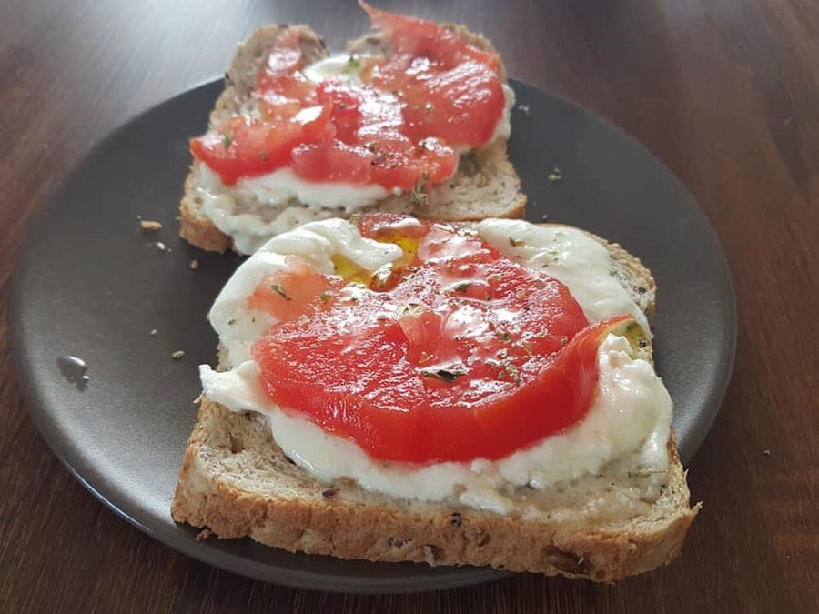 plate with 'Bekas Family Farm' fresh cream cheese and cutting tomatos on the top on bread