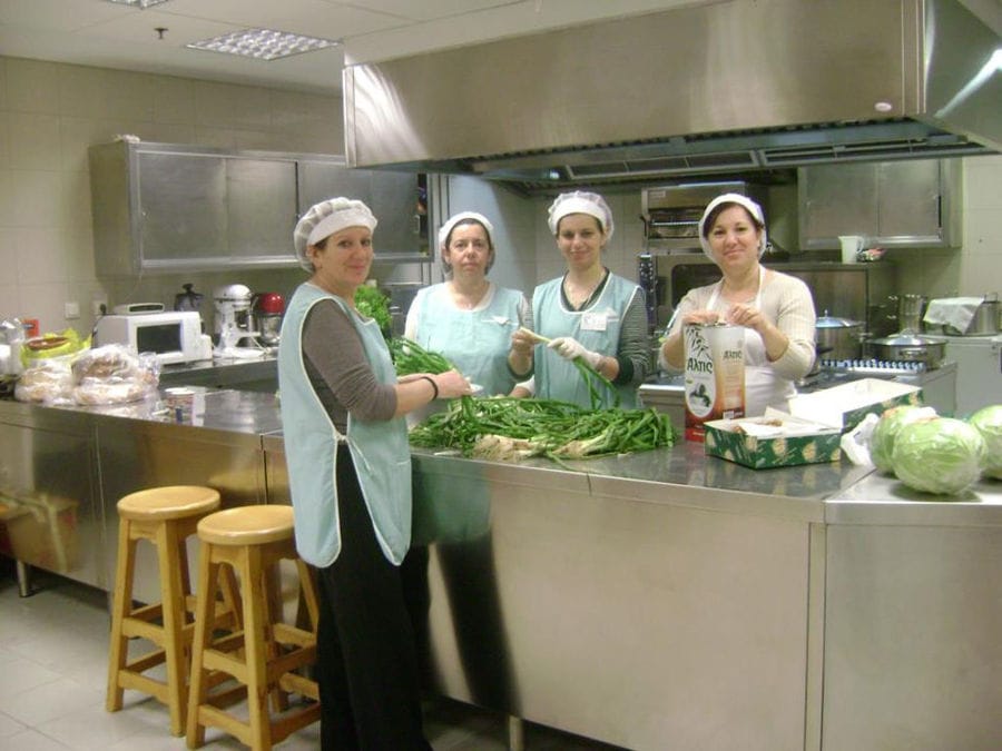 women smiling at the camera and cooking fresh vegetables at 'Agrotouristic Women's Cooperative of Mesotopos Lesvos' workshop