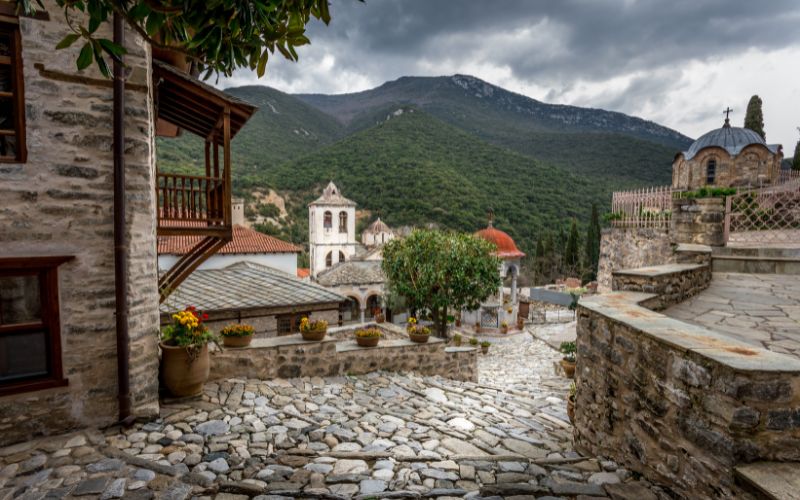 a stone walkway with a stone building and trees in the background