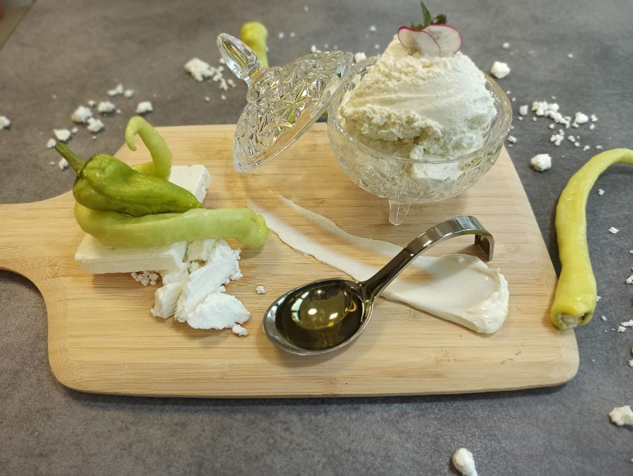 bowl with fresh cream cheese and a piece of 'feta' cheese with peppers on the top and a teaspoon with oil from 'Pitenis'